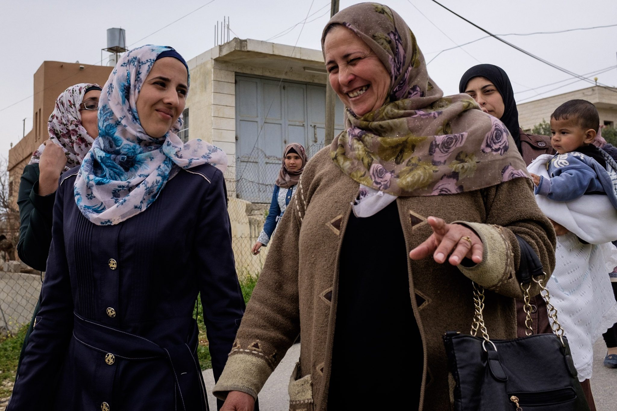 a smiling palestinian woman in a flowery hijab walkes with a group of other women in hijabs (West Bank, Palestine)